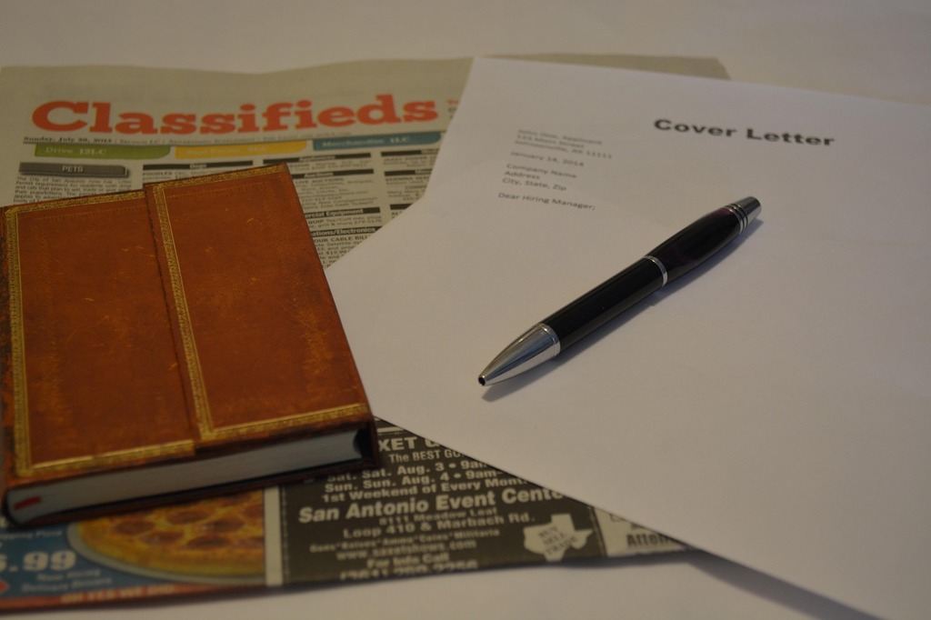 Close-up of a cover letter and pen placed on top of a newspaper classifieds section, with a small leather notebook beside them, representing a job search or career application process. Image by Trudi Nichols from Pixabay